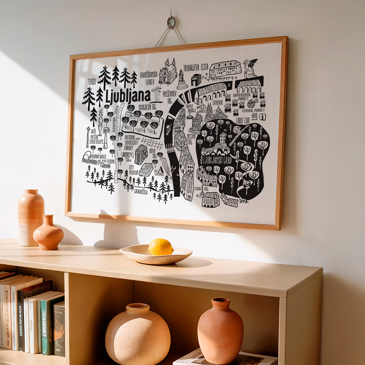 Framed map of Ljubljana on a wall above a shelf with decorative items.
