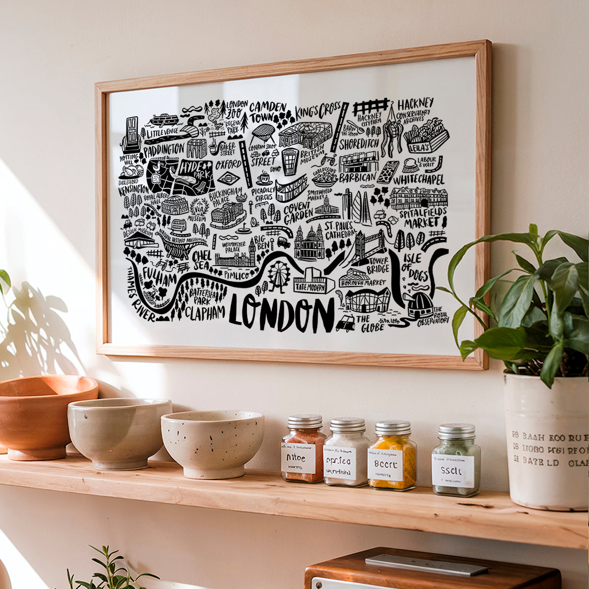 Framed map of London on a wall above a shelf with bowls and jars.