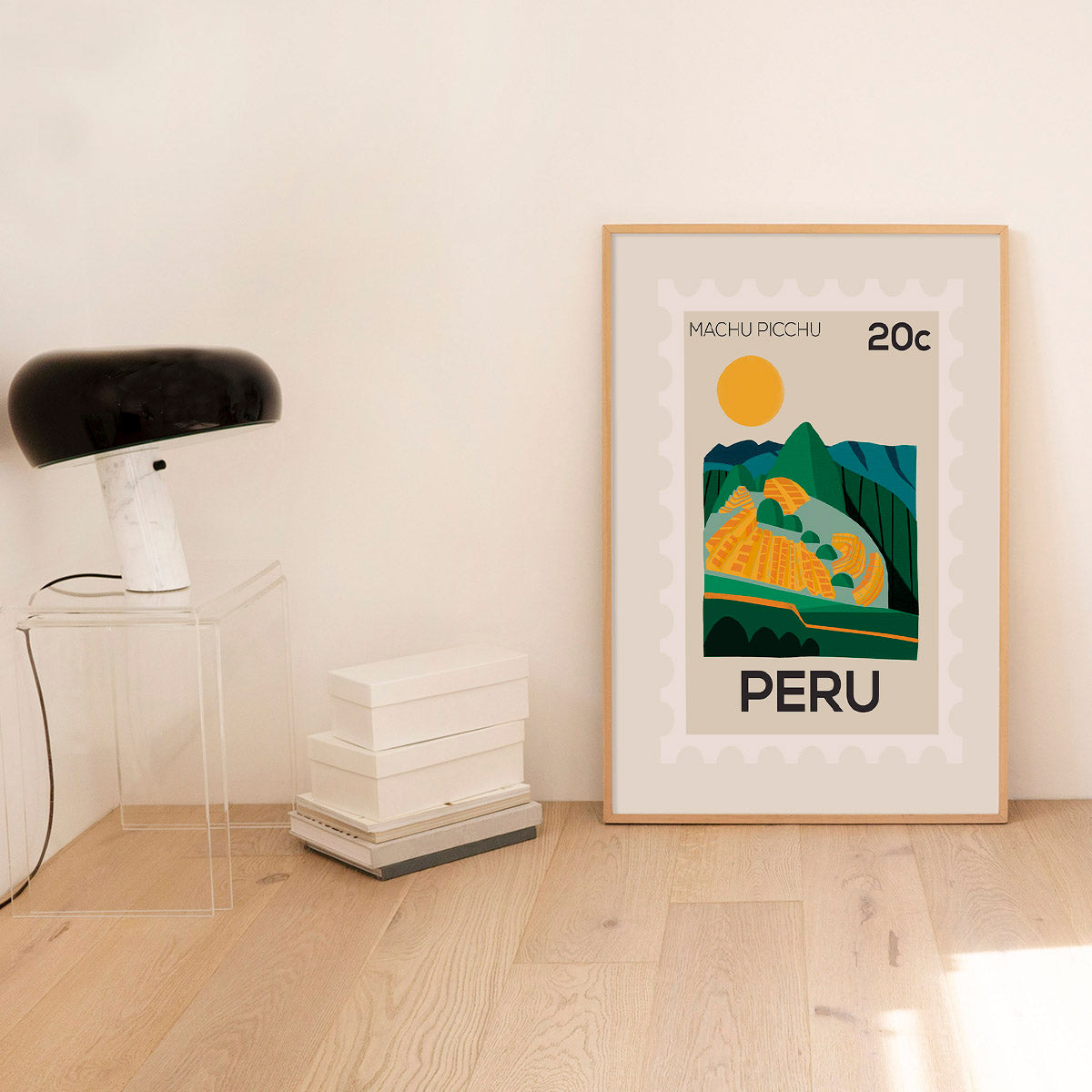 Framed poster of Machu Picchu with 'PERU' text in a room with a lamp and books.