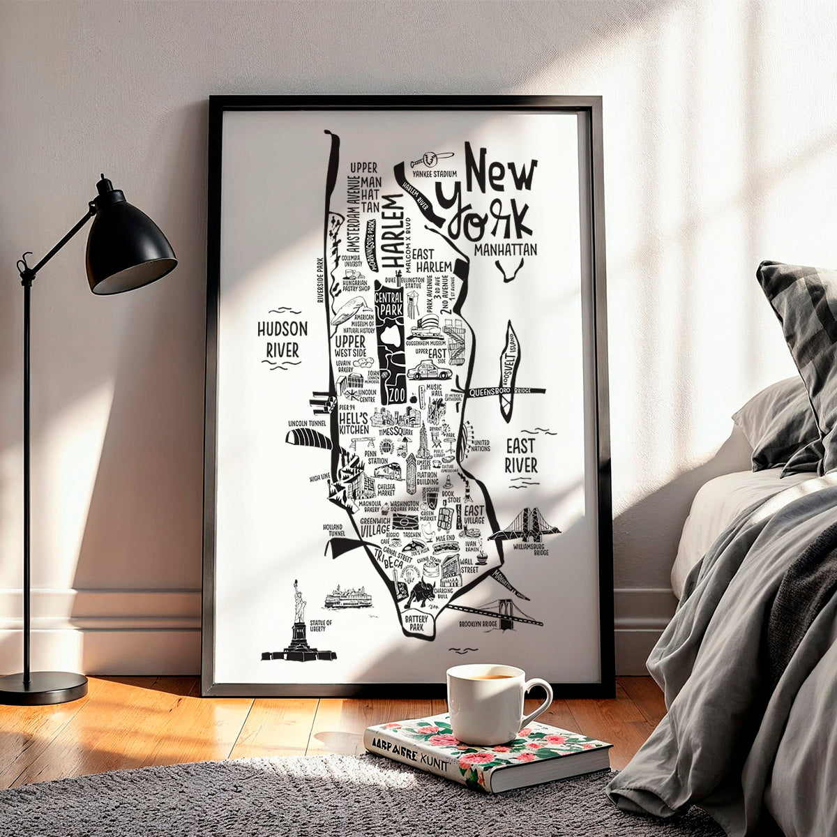 Framed black and white map of New York City in a room with a lamp and book on a rug.