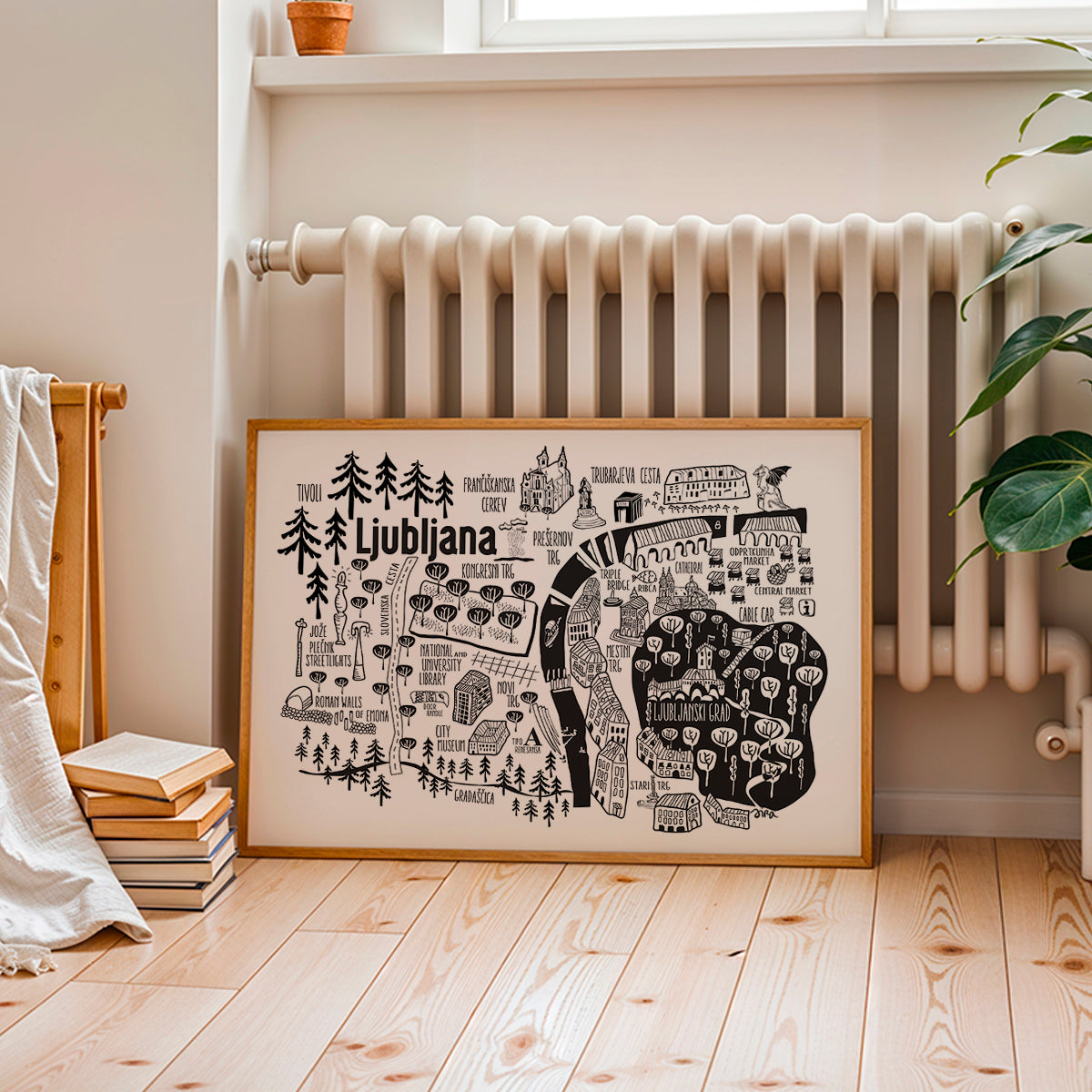 Framed map of Ljubljana on a wall in a room with a radiator and books.