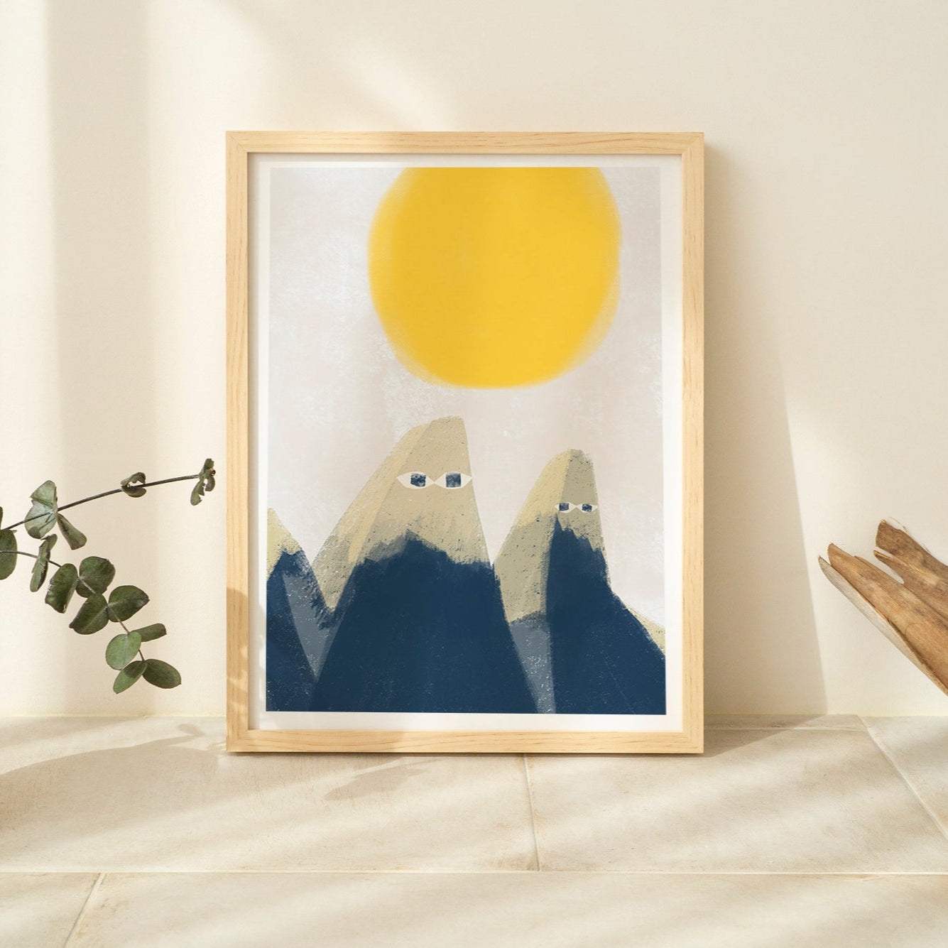 Framed artwork of mountains and a sun on a wall with decorative elements.