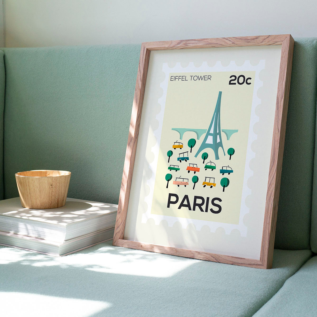 Framed poster of the Eiffel Tower with 'Paris' text on a light green couch.