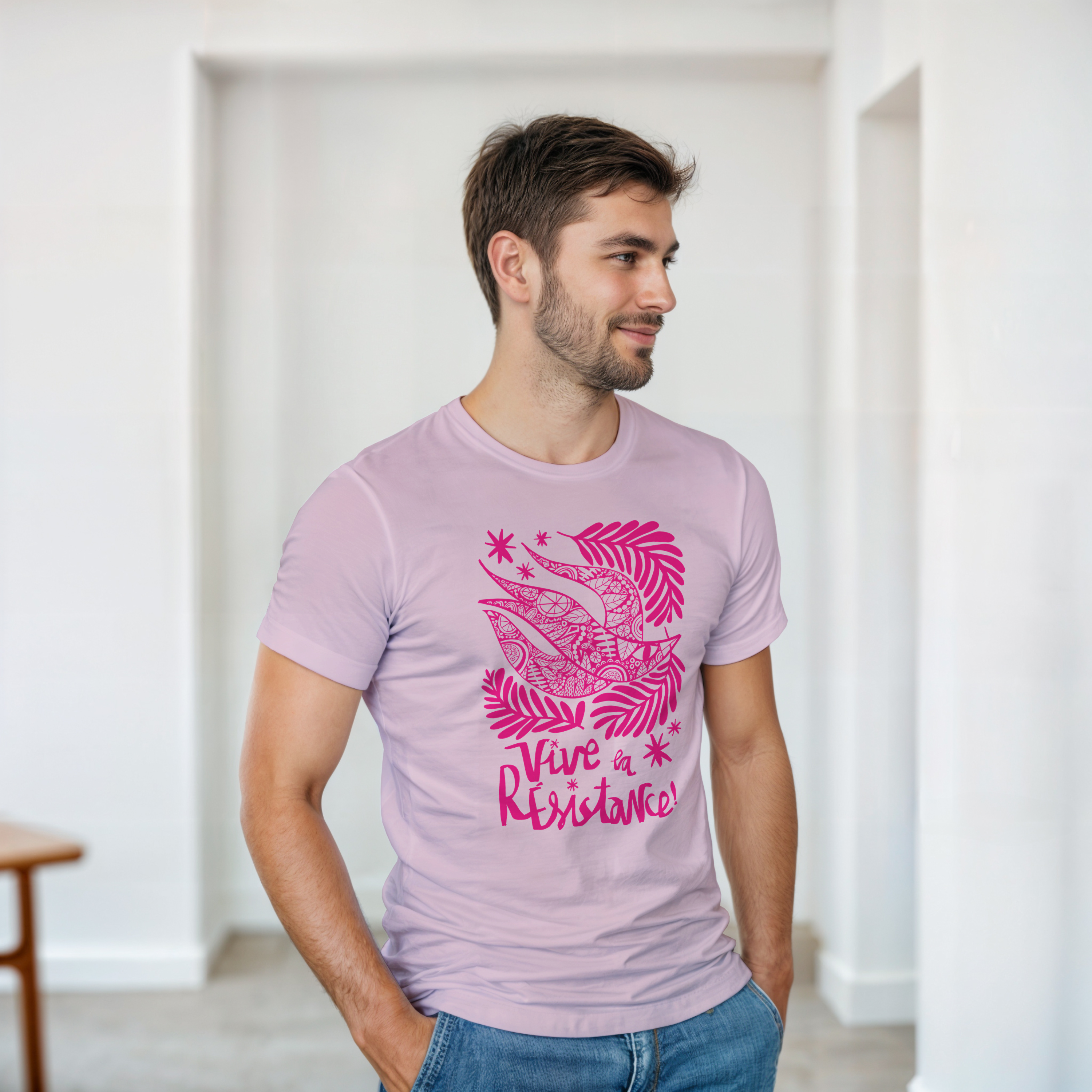 Man wearing a light purple t-shirt with pink graphic design and text indoors.