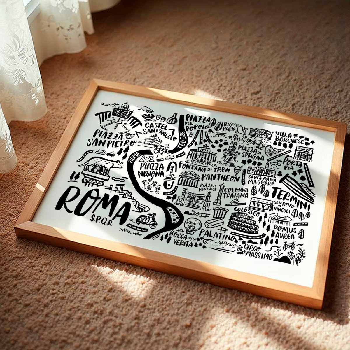 Framed map of Rome with black illustrations on a white background, placed on a textured surface.