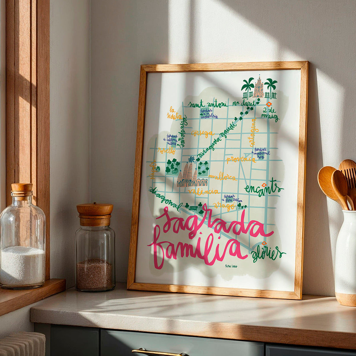 Framed artwork of Sagrada Familia in BArcelona with colorful text and illustrations on a kitchen counter