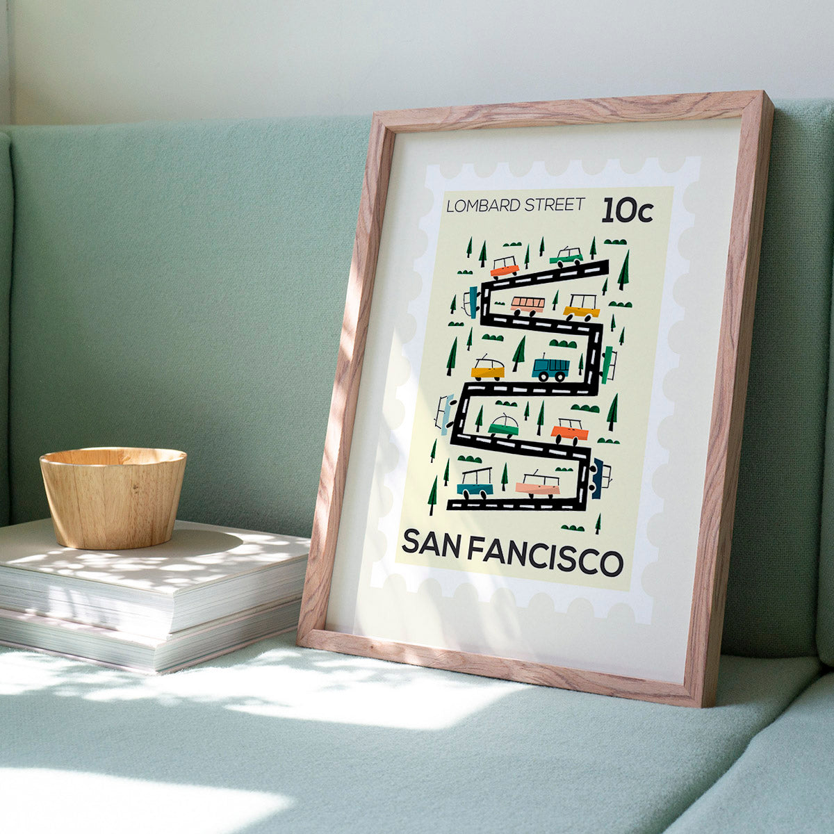Framed artwork of San Francisco's Lombard Street with a wooden frame on a light green couch.
