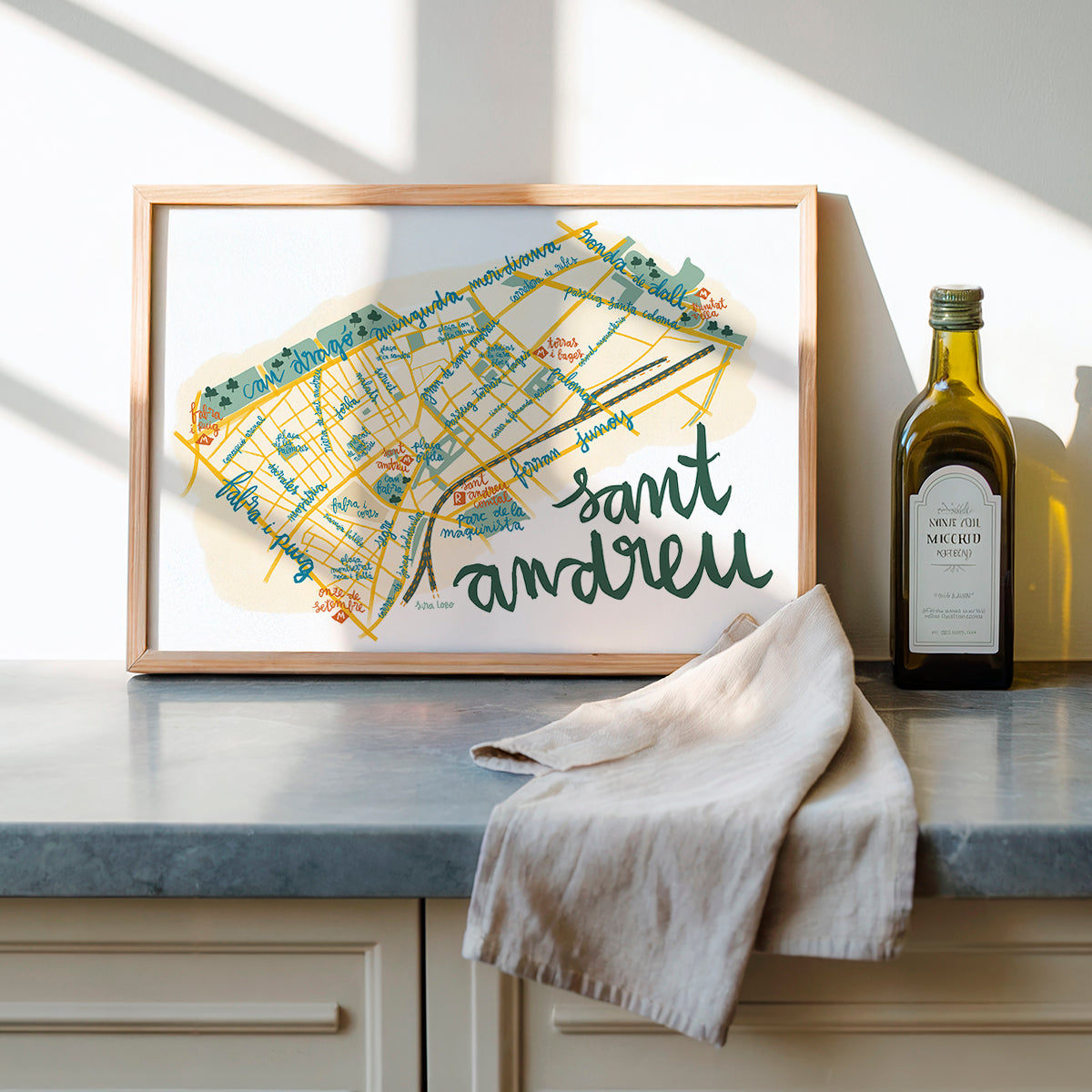 Framed map of Saint Andrews on a kitchen counter with a bottle of olive oil.