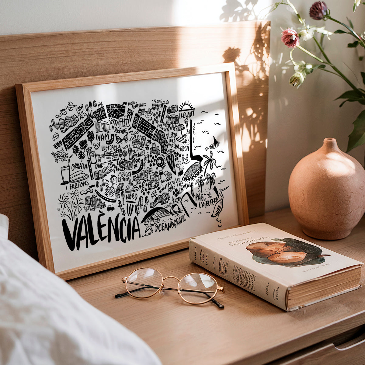 Framed map of Valencia on a wooden surface with a book and glasses.