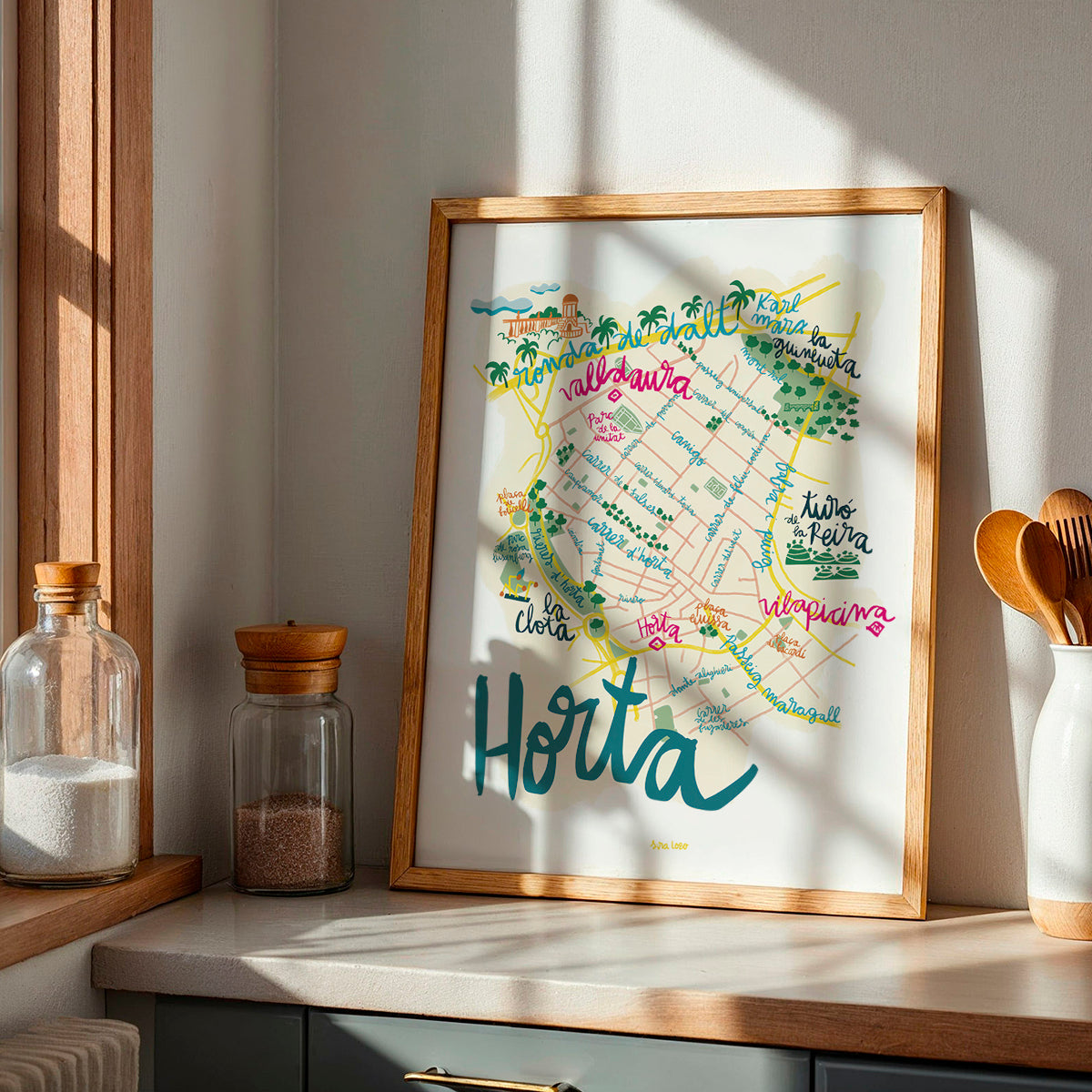 Framed map of Horta on a kitchen counter with jars and utensils.