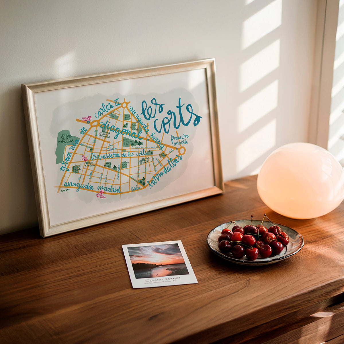 Framed map on a wooden surface with cherries and a photo