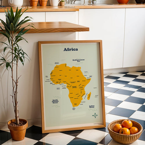 Framed map of Africa on a checkered floor with a plant and basket of oranges in a kitchen.
