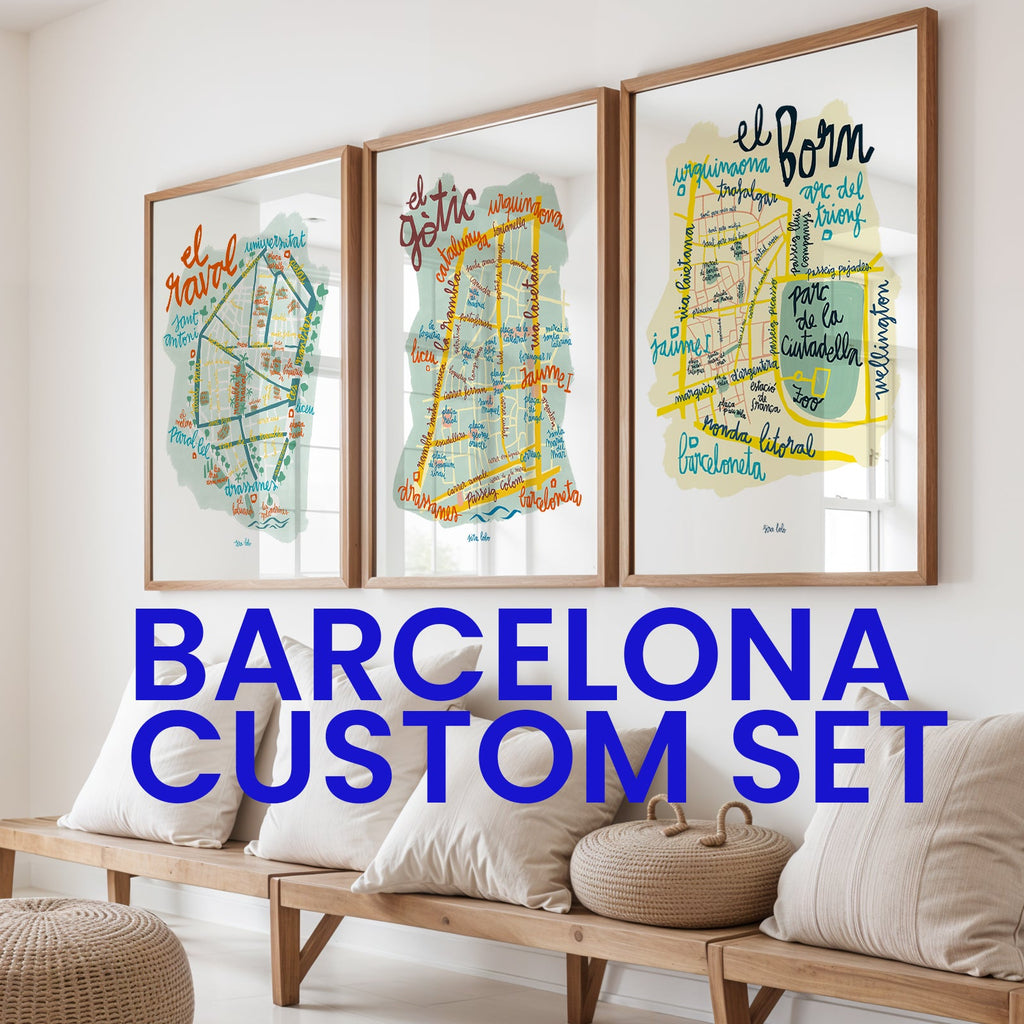 Three framed maps of Barcelona on a wall above a wooden bench with decorative pillows.