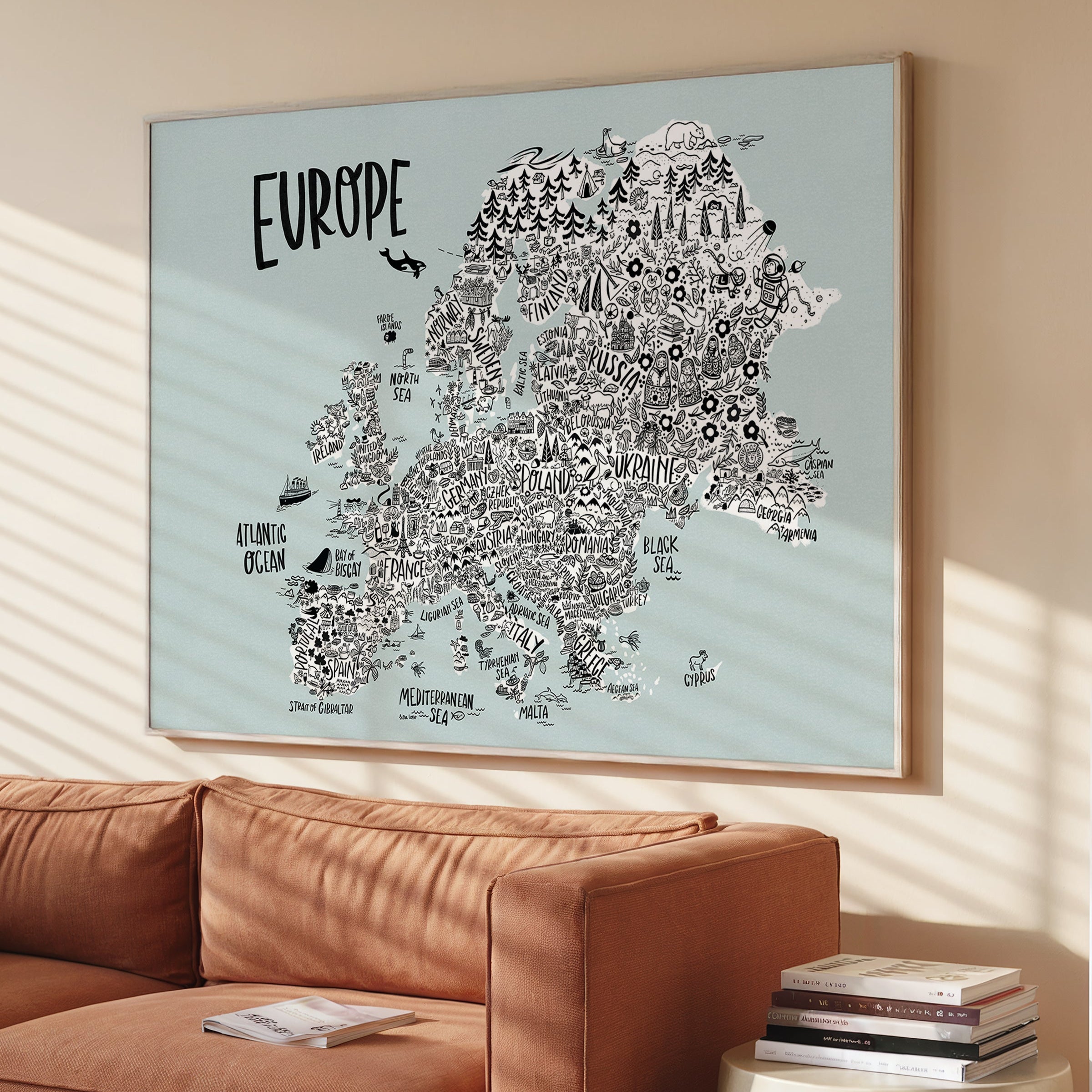 Framed map of Europe on a wall above a brown sofa.