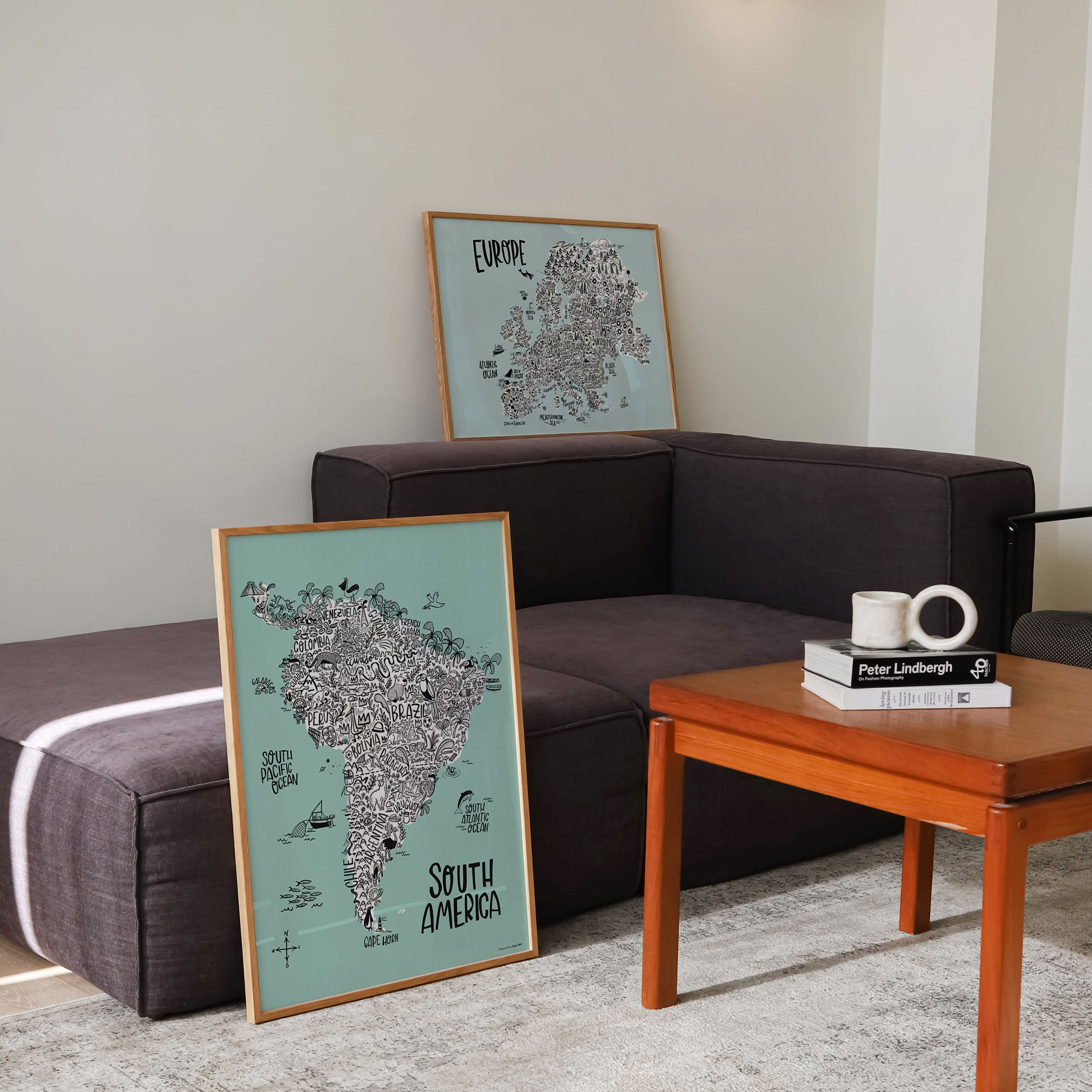 Living room with a brown sofa, wooden coffee table, and framed maps on the wall.