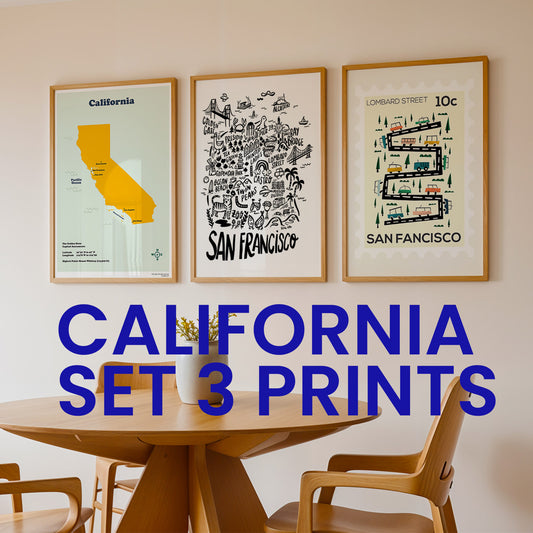Three framed prints on a wall above a wooden table with chairs.