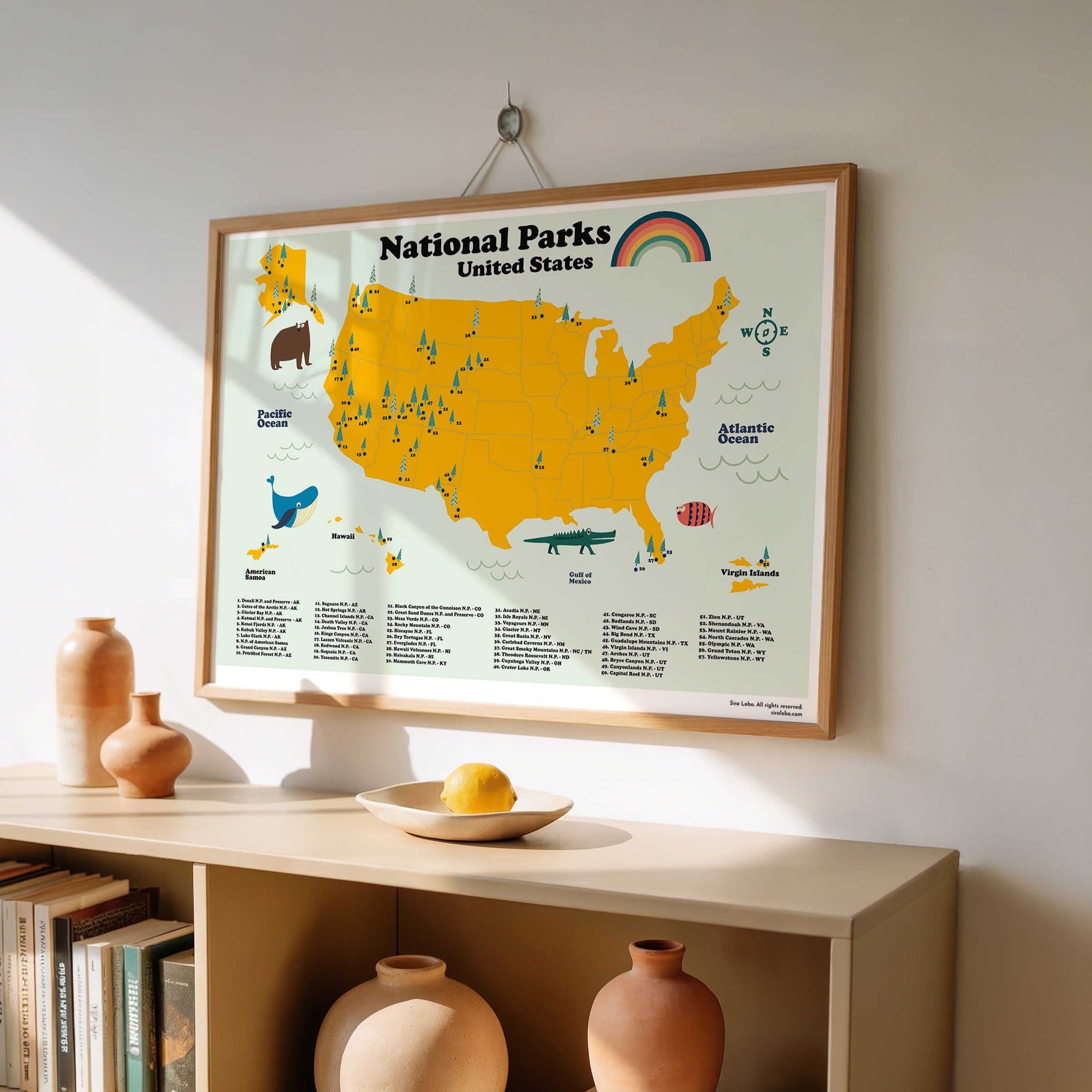 Framed map of National Parks in the United States on a wall above a shelf with decorative items.