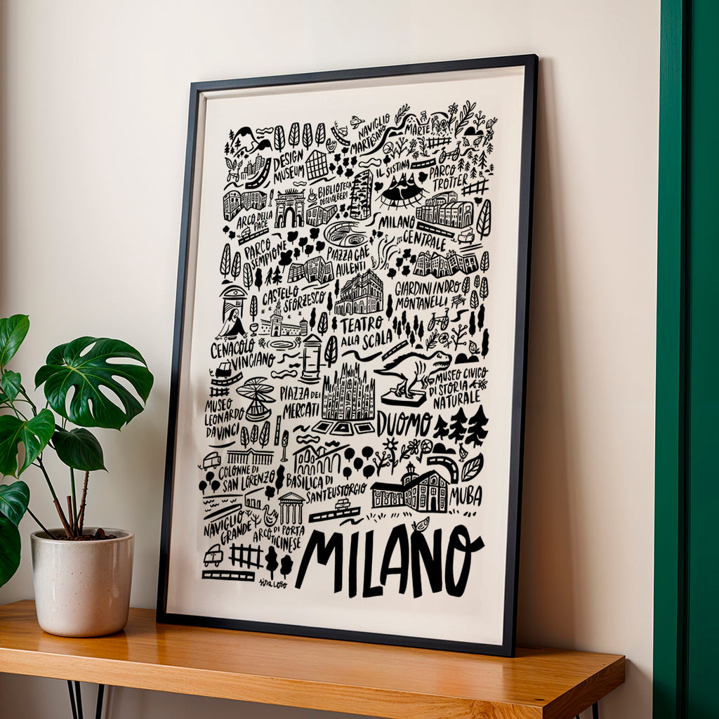 Framed artwork with 'Milano' on a wall next to a plant