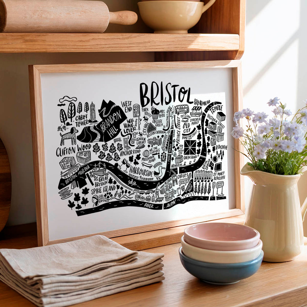 Framed map of Bristol on a kitchen counter with bowls and flowers.