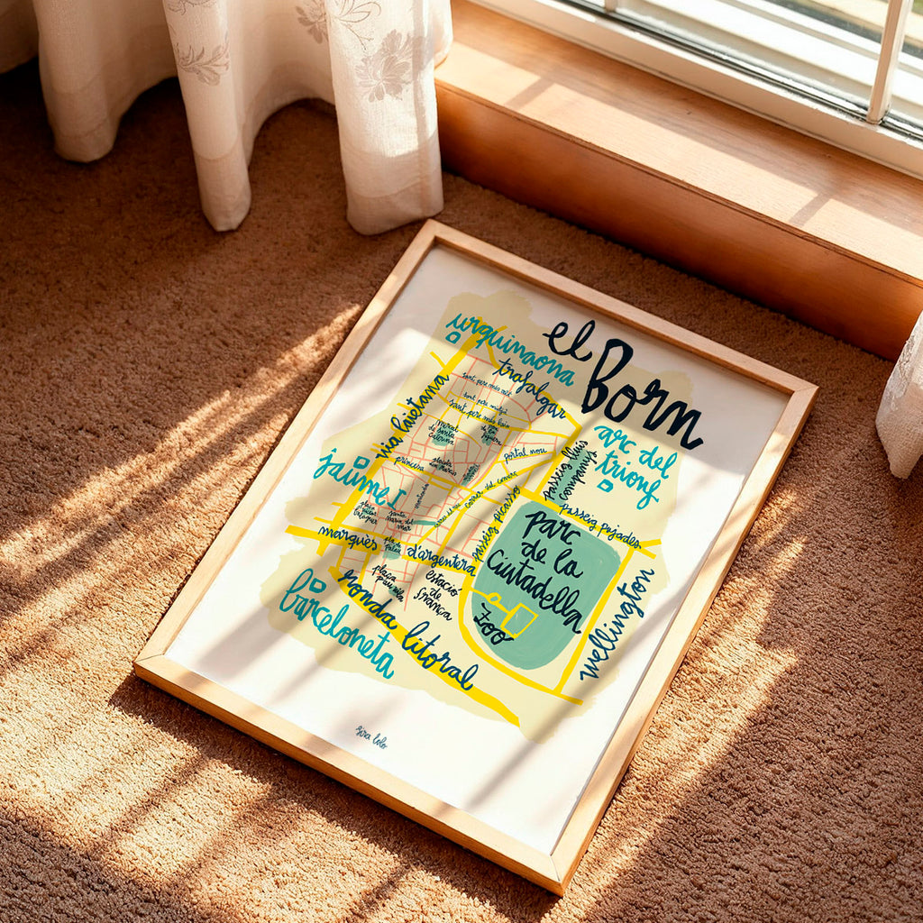 Framed map of El Born district in Barcelona on a carpeted floor with sunlight casting shadows.