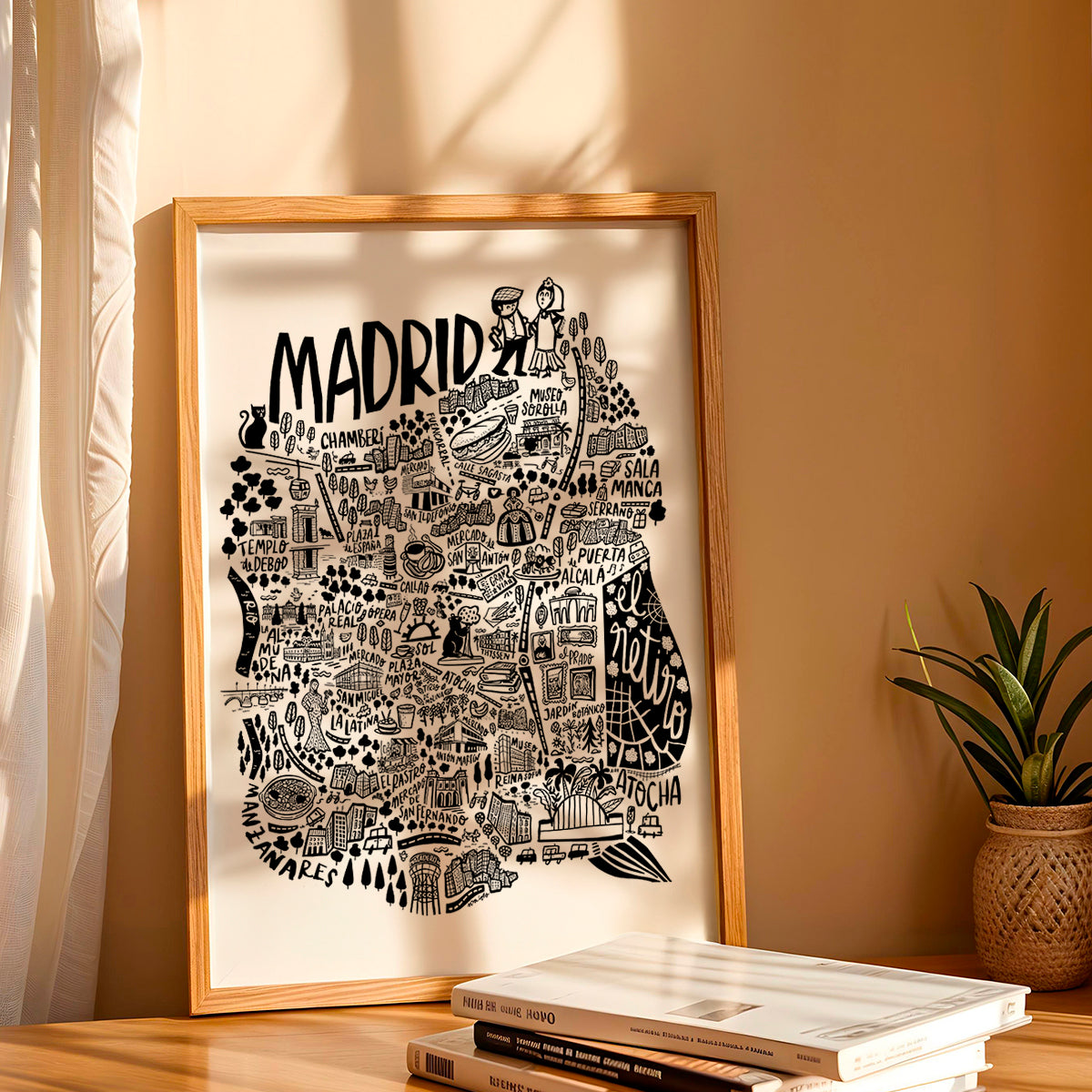 Framed map of Madrid on a wall with books and a plant below