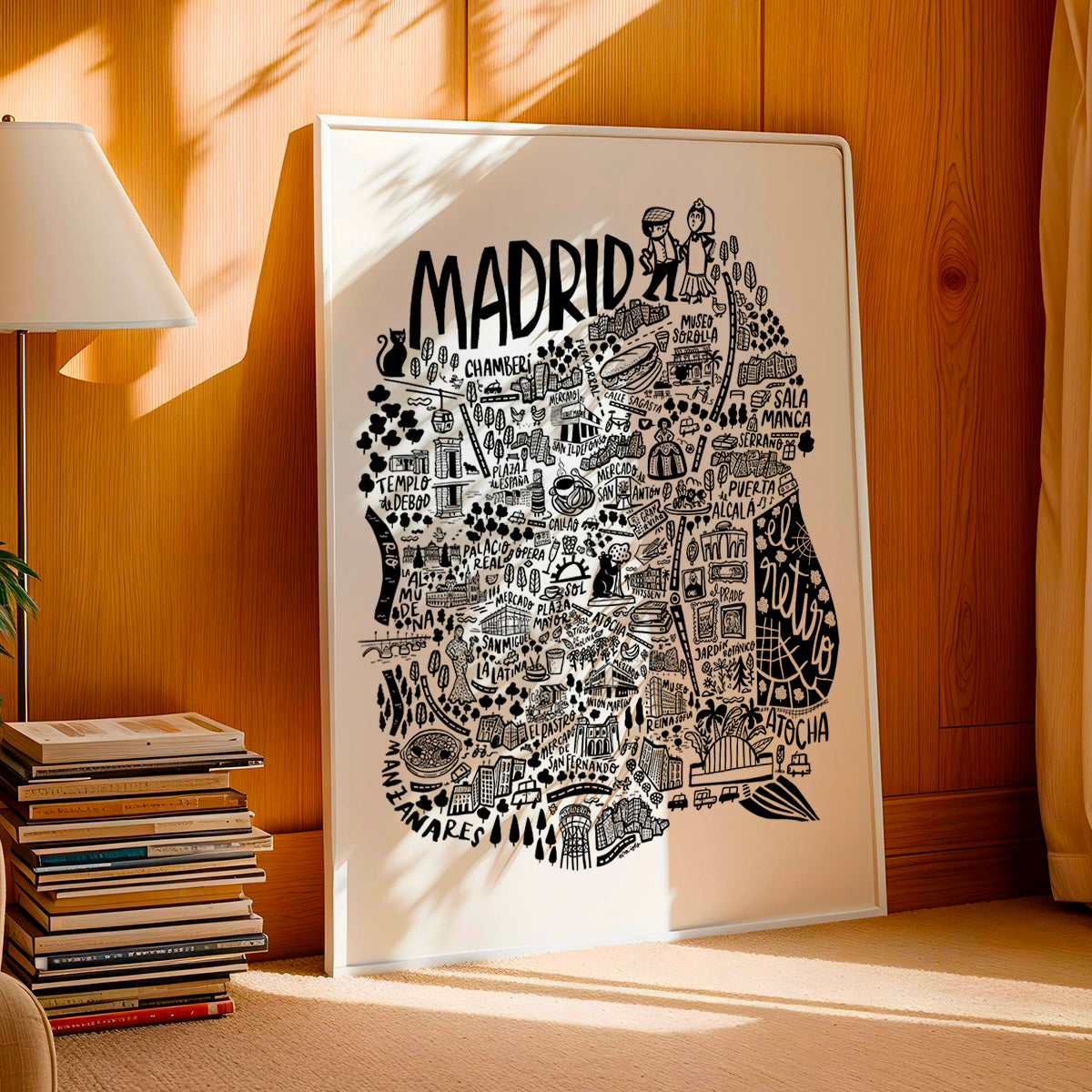Framed map of Madrid on a wooden wall with books and a lamp in the background