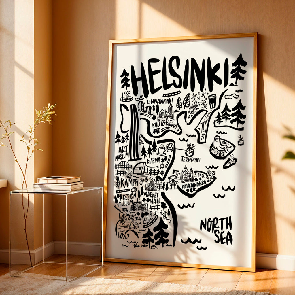 Framed map of Helsinki on a wall in a room with a side table and plant.
