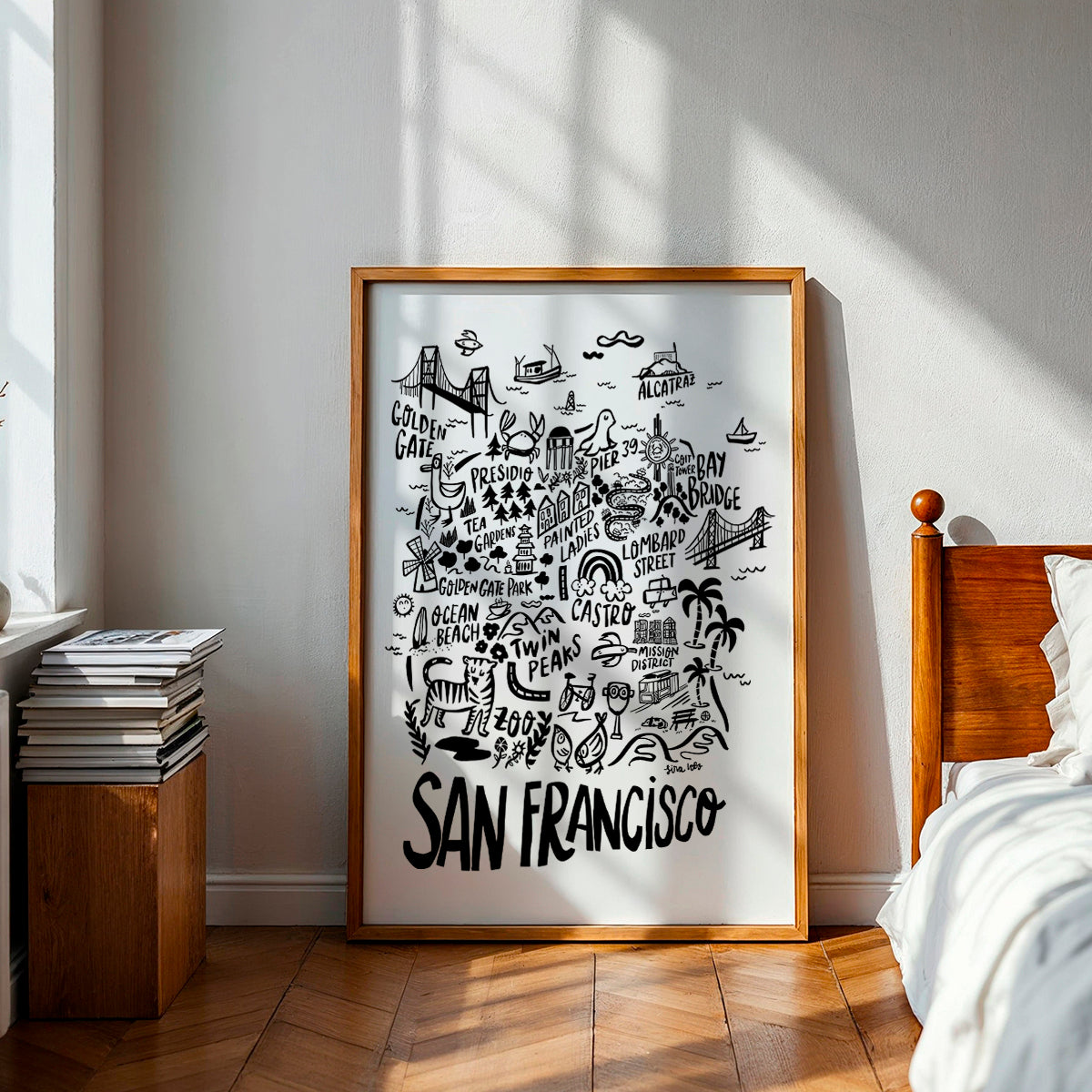 Framed poster of San Francisco with black illustrations on a white background, placed in a room with wooden furniture and a bed.