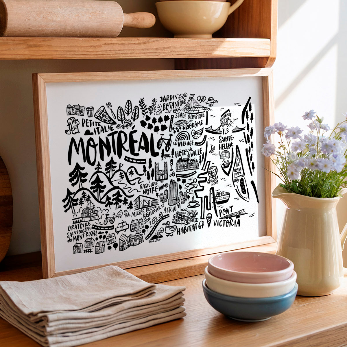 Framed artwork with 'Montreal' design on a wooden shelf with kitchen items.