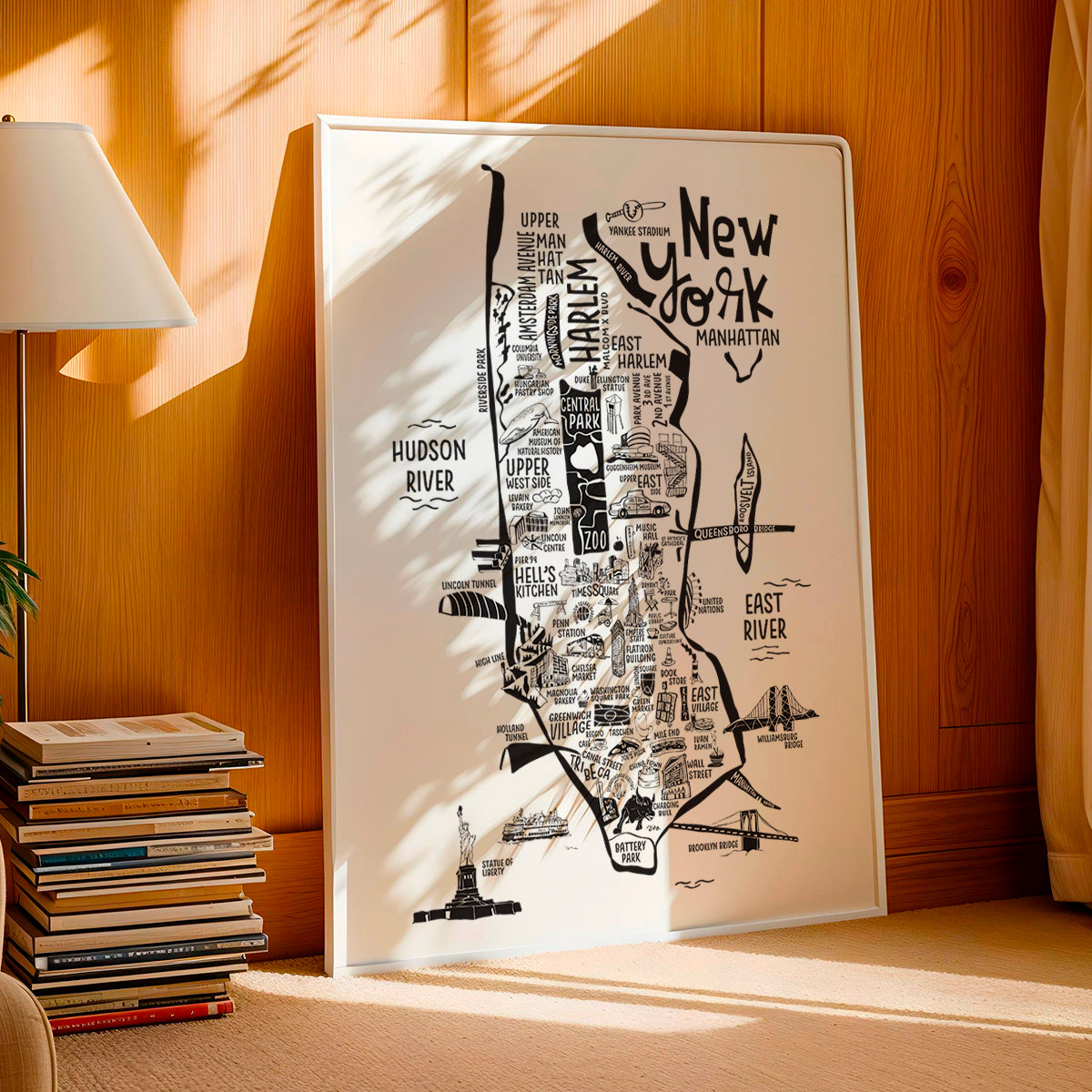 Framed map of New York City on a wall with books and a lamp in the background