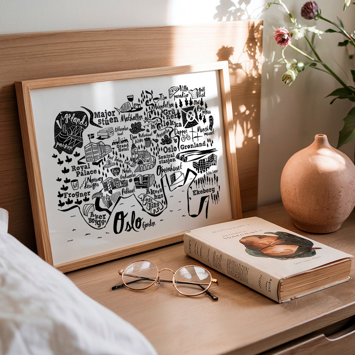 Framed map of Oslo on a wooden surface with a book and glasses.