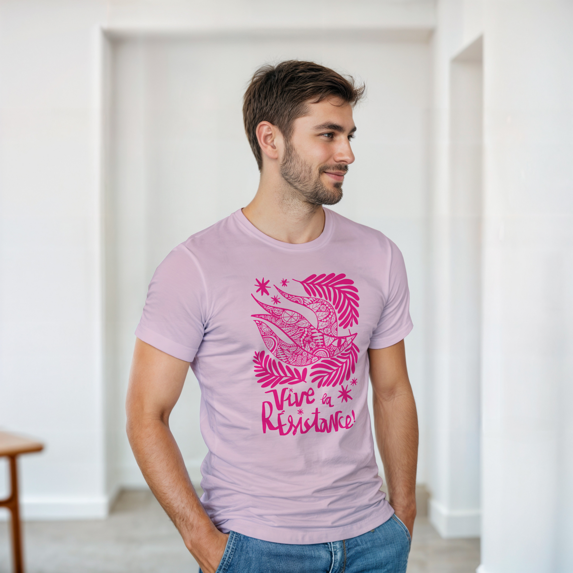 Man wearing a light purple t-shirt with pink graphic design and text indoors.