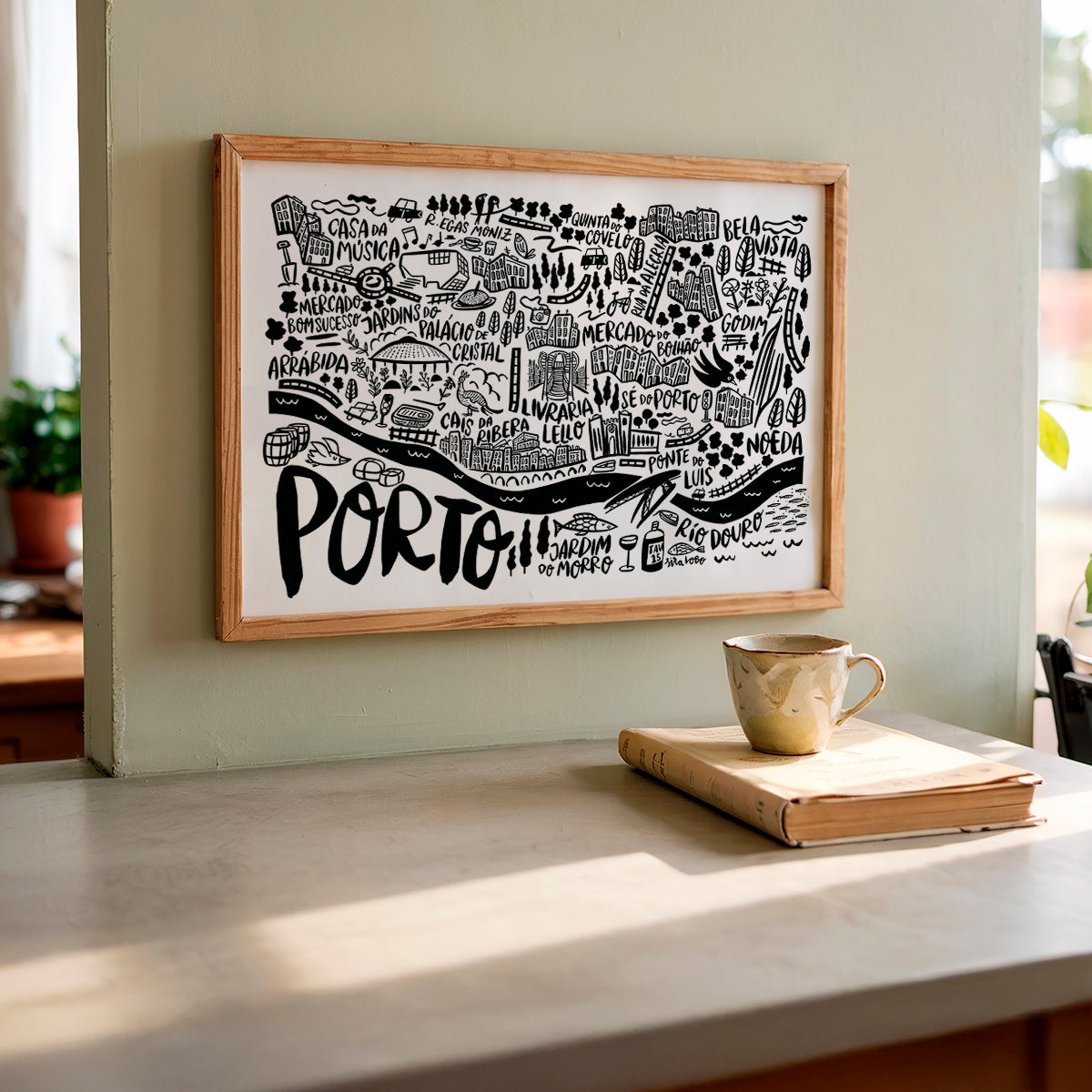 Framed map of Portland on a wall above a table with a mug and book.