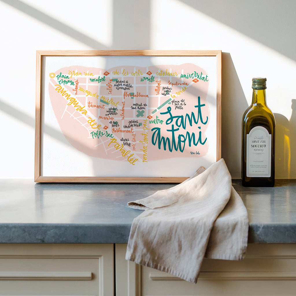 Framed artwork with colorful text on a kitchen counter next to a bottle of olive oil.