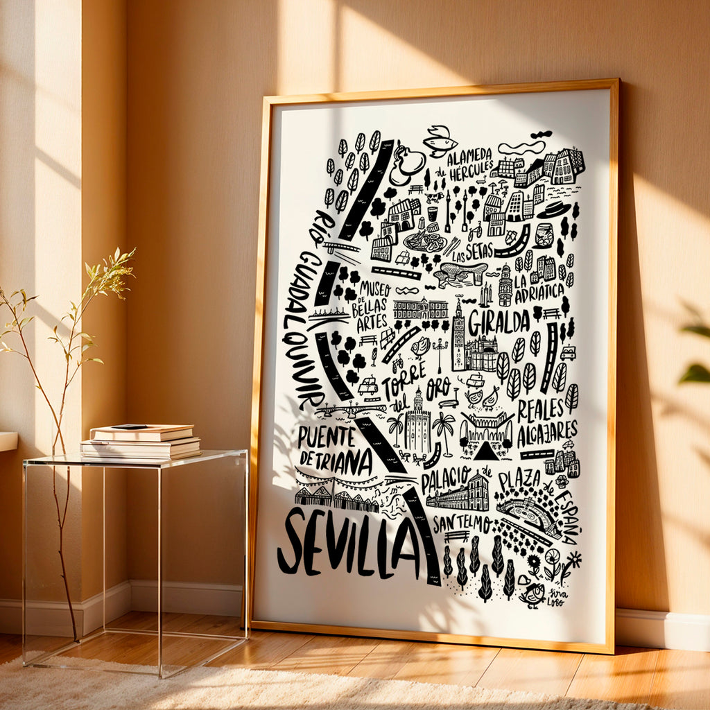Framed artwork of a map of Sevilla with black illustrations on a white background, placed on a wooden floor.