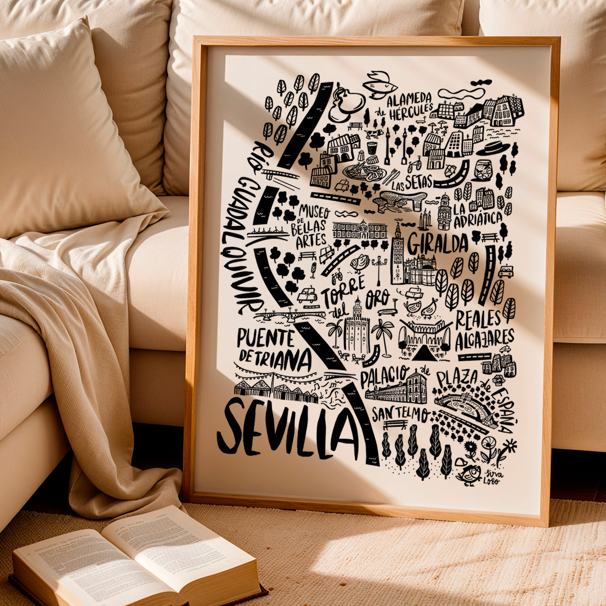 Framed map of Sevilla with decorative elements on a beige couch.