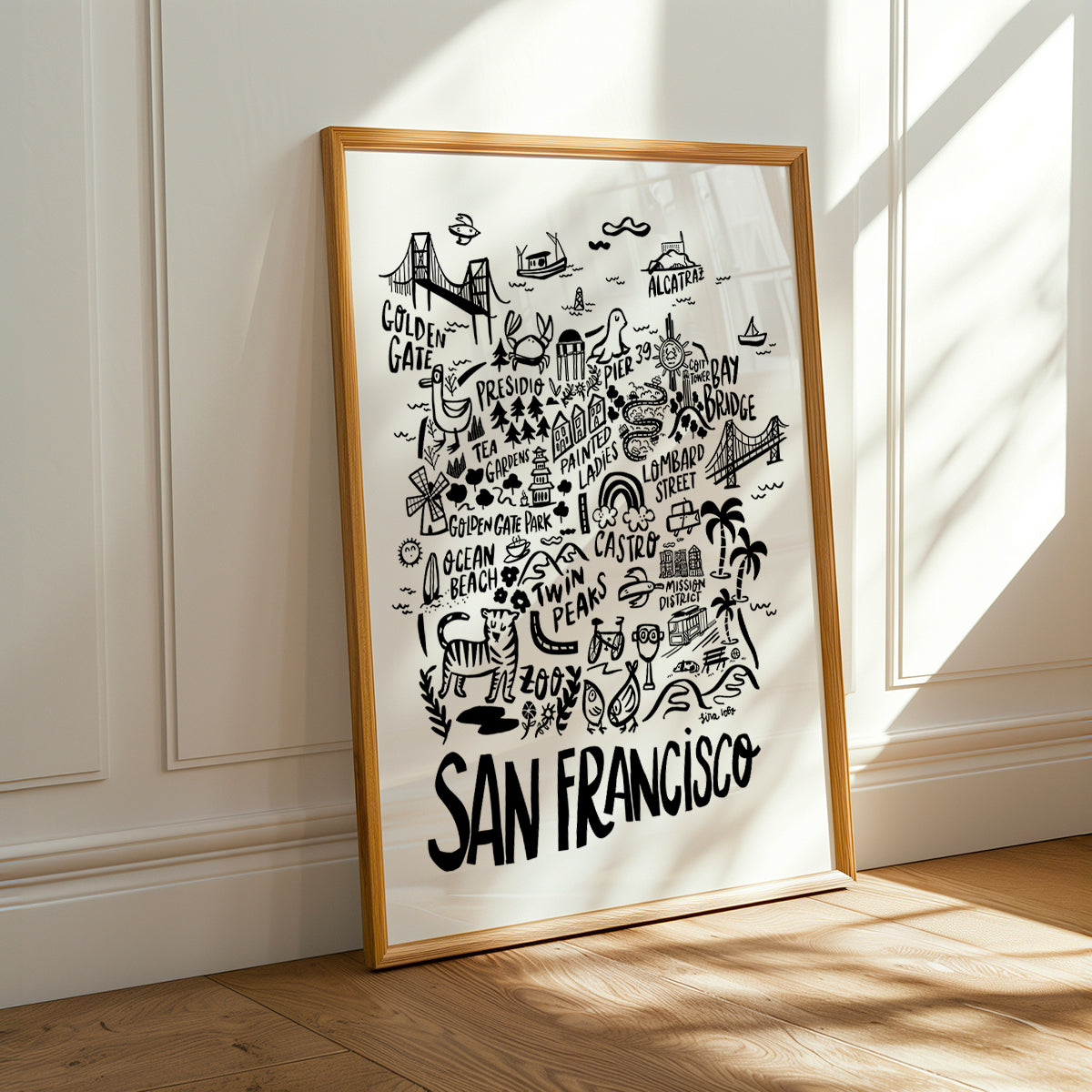 Framed map of San Francisco on a white wall with sunlight casting shadows.