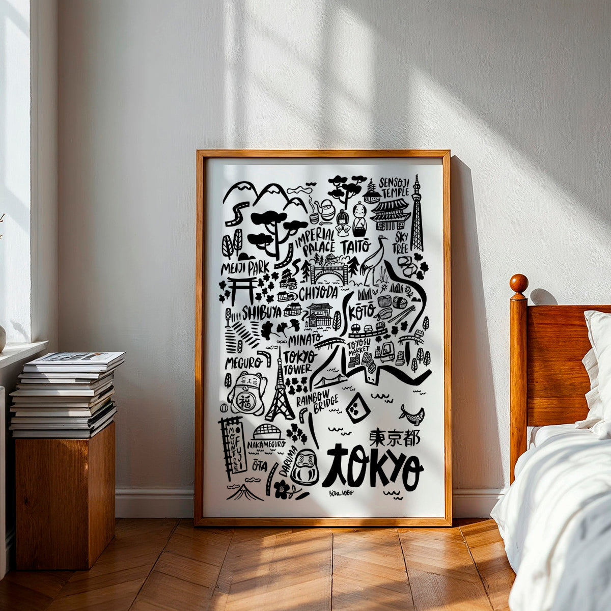 Framed map of Tokyo in a bedroom with wooden headboard and books.