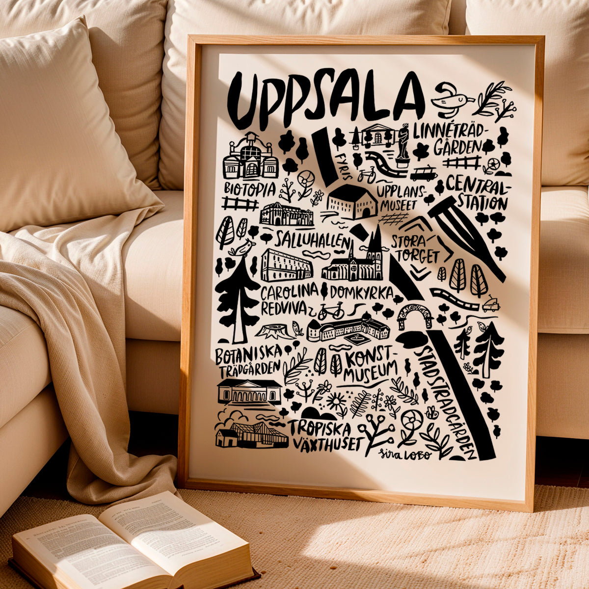Framed artwork of Uppsala with landmarks on a beige couch background