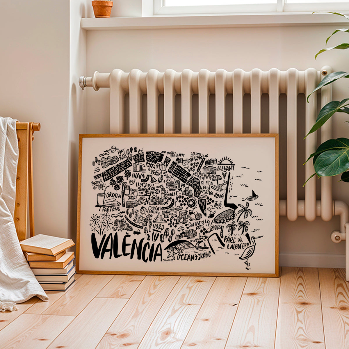 Framed map of Valencia on a wall in a room with a radiator and books.